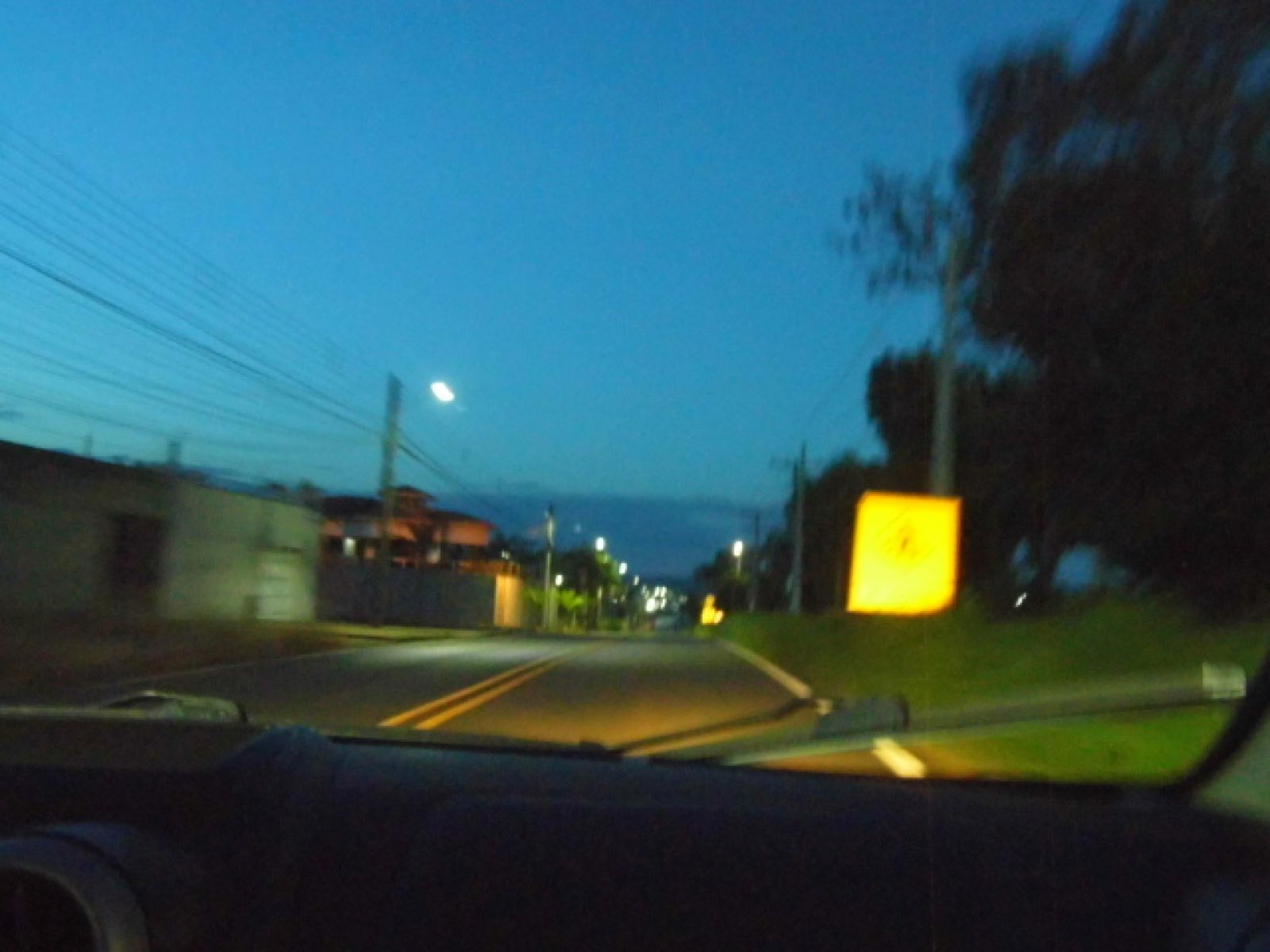 Estrada na hora azul vista de dentro do carro, com placa amarela brilhando